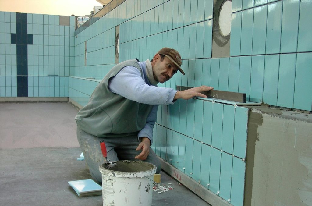 A man is working on a wall with tiles